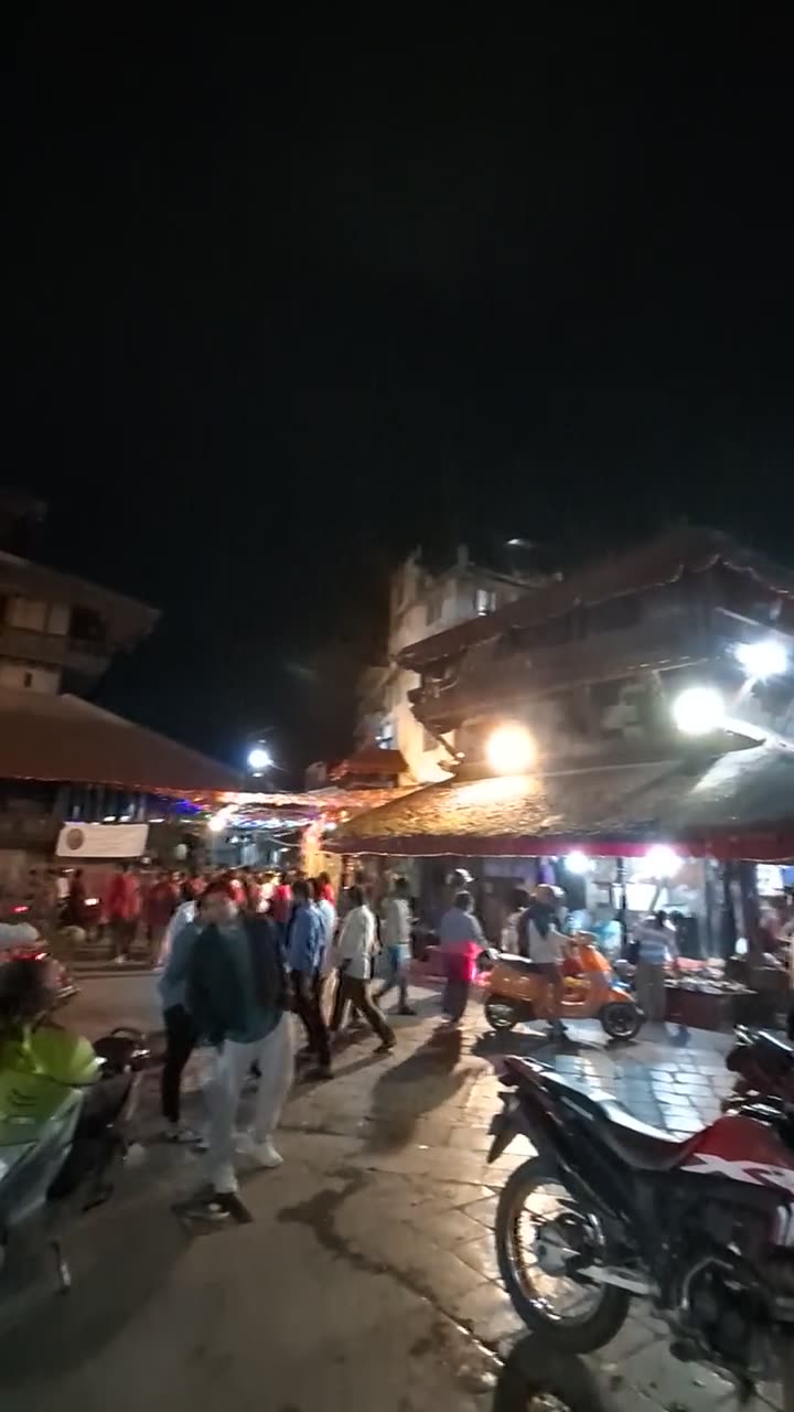 Temples, lit market stalls and parked motorbikes in Kathmandu Durbar Square at night
