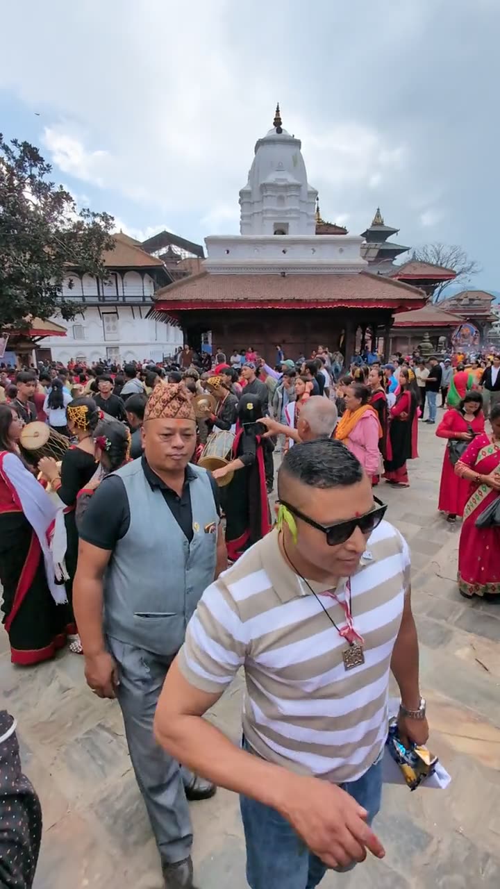 Newar musicians in traditional dress playing dhime drums and cymbals in a crowd in Kathmandu Durbar Square
