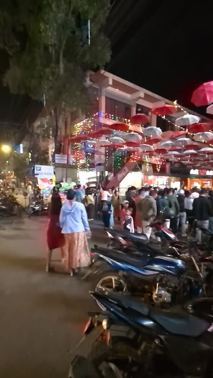 A crowded street at night under rows of red and white paper umbrellas and lights